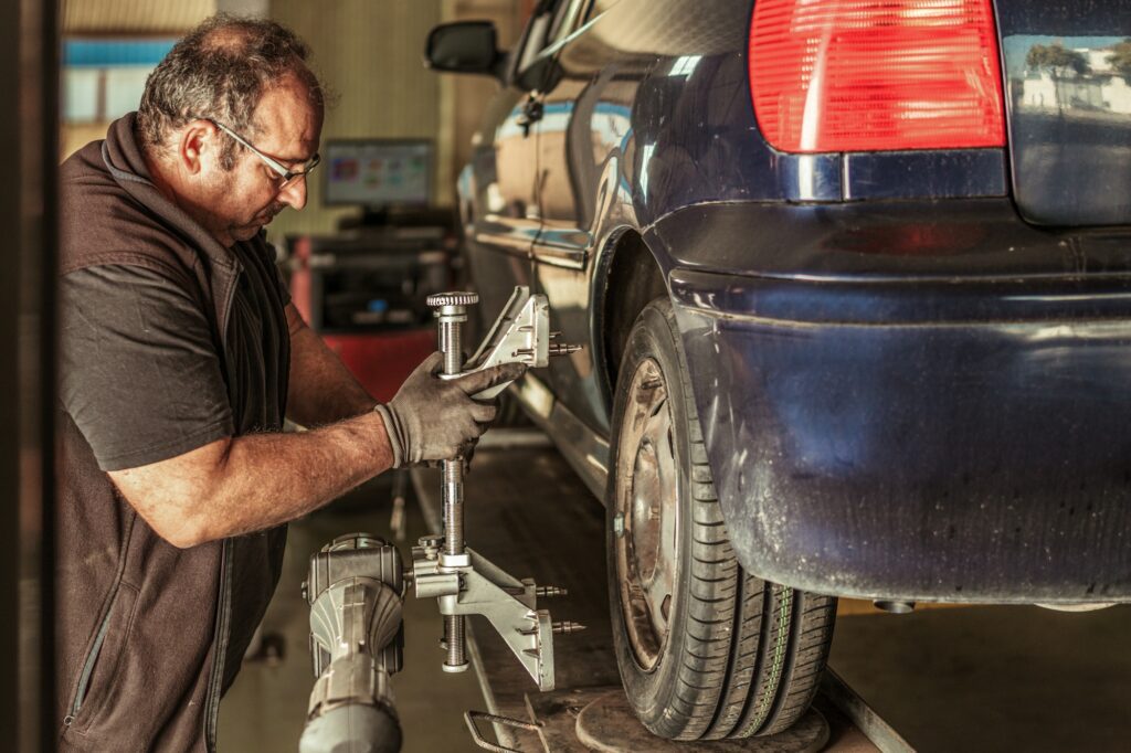 Profile of a mechanic repairing the steering alignment of a blue car